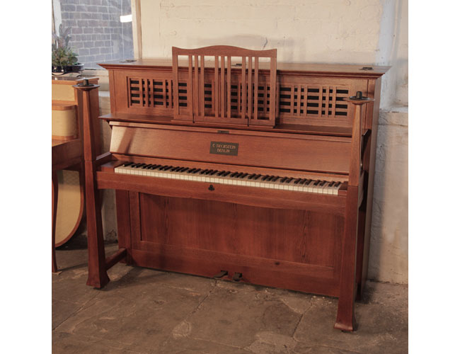 Arts and Crafts, 1905, Bechstein model 9 upright piano with an oak case. Cabinet features statement iron hinges. Part of the cabinet design, the large sculptural candlesticks sit atop the square piano legs.