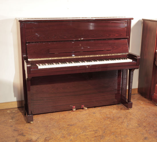 As new, 2009, Steinway model V upright piano with a mahogany gloss case and brass fittings. Piano has an eighty-eight note keyboard and two pedals. 