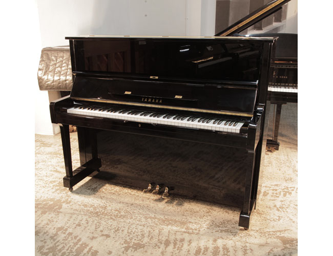 Reconditioned, 1977, Yamaha U1 upright piano in black gloss with brass fittings. Piano has an eighty-eight note keyboard and three pedals
